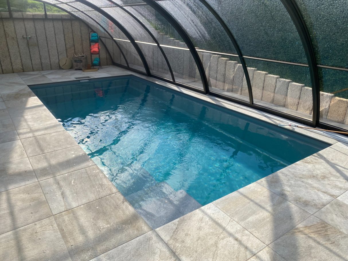 Ein neu gestalteter Indoor-Pool mit klarem Wasser und durchsichtiger Überdachung.